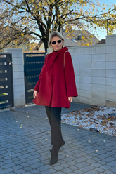 a lady in a red wool coat and a pair of black pants